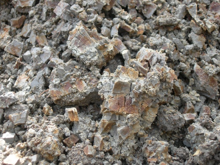 En sur sulfatjord som kommit i kontakt med luftens syre. Den har röda, gula och rödbruna fält mot en grå bakgrund.